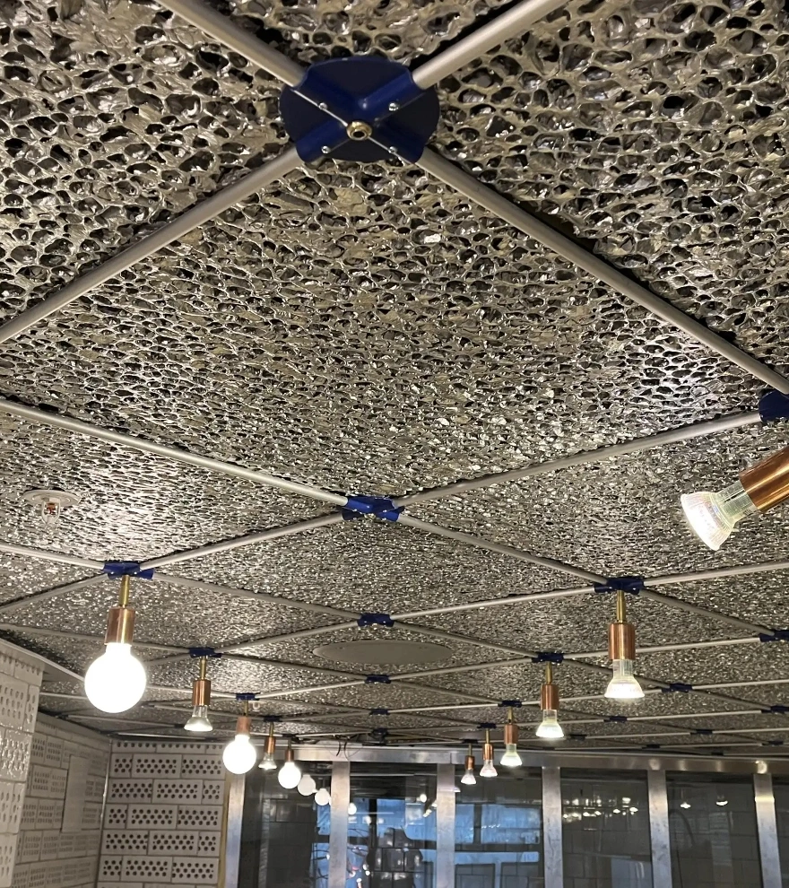 Rosett Ceiling på Sturehof: perforerat undertak med mässingsprofiler och rosetter
